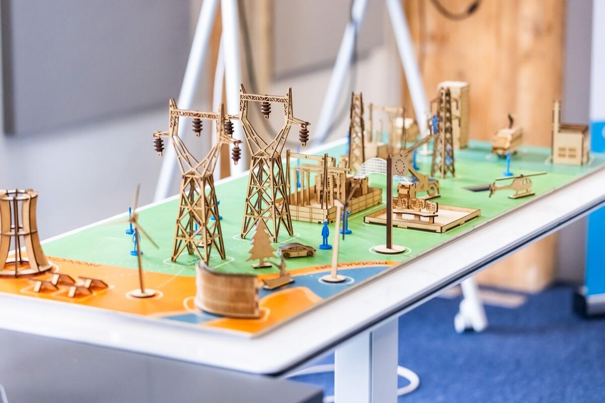 Maquette en bois découpé au laser : pylônes, lignes et centrale électrique sur un plateau