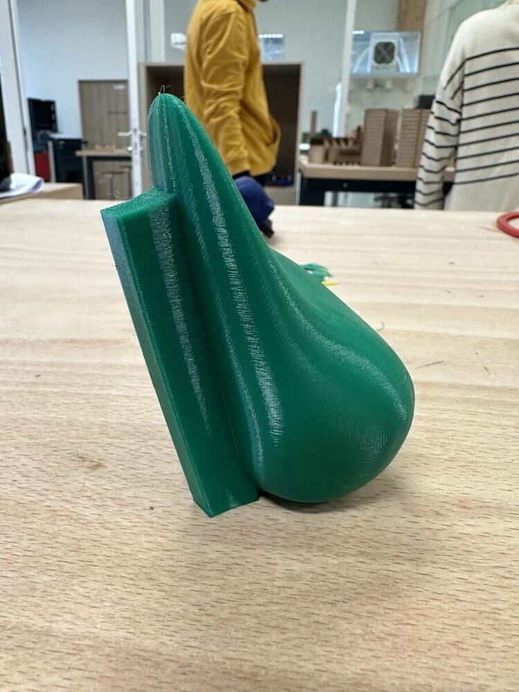 Pièce verte imprimée en 3D posée sur une table d'atelier